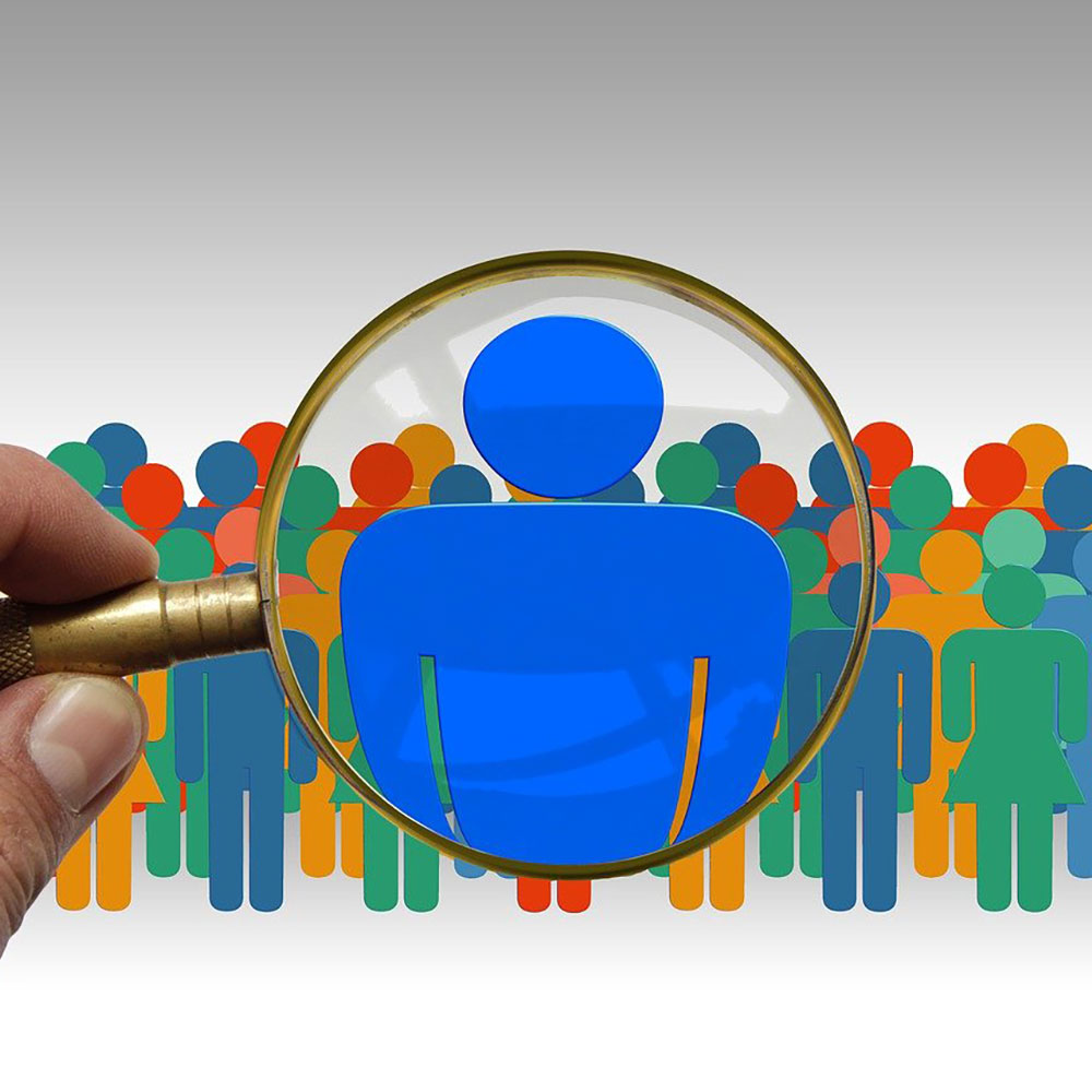 Magnifying glass singling out one person in a crowd